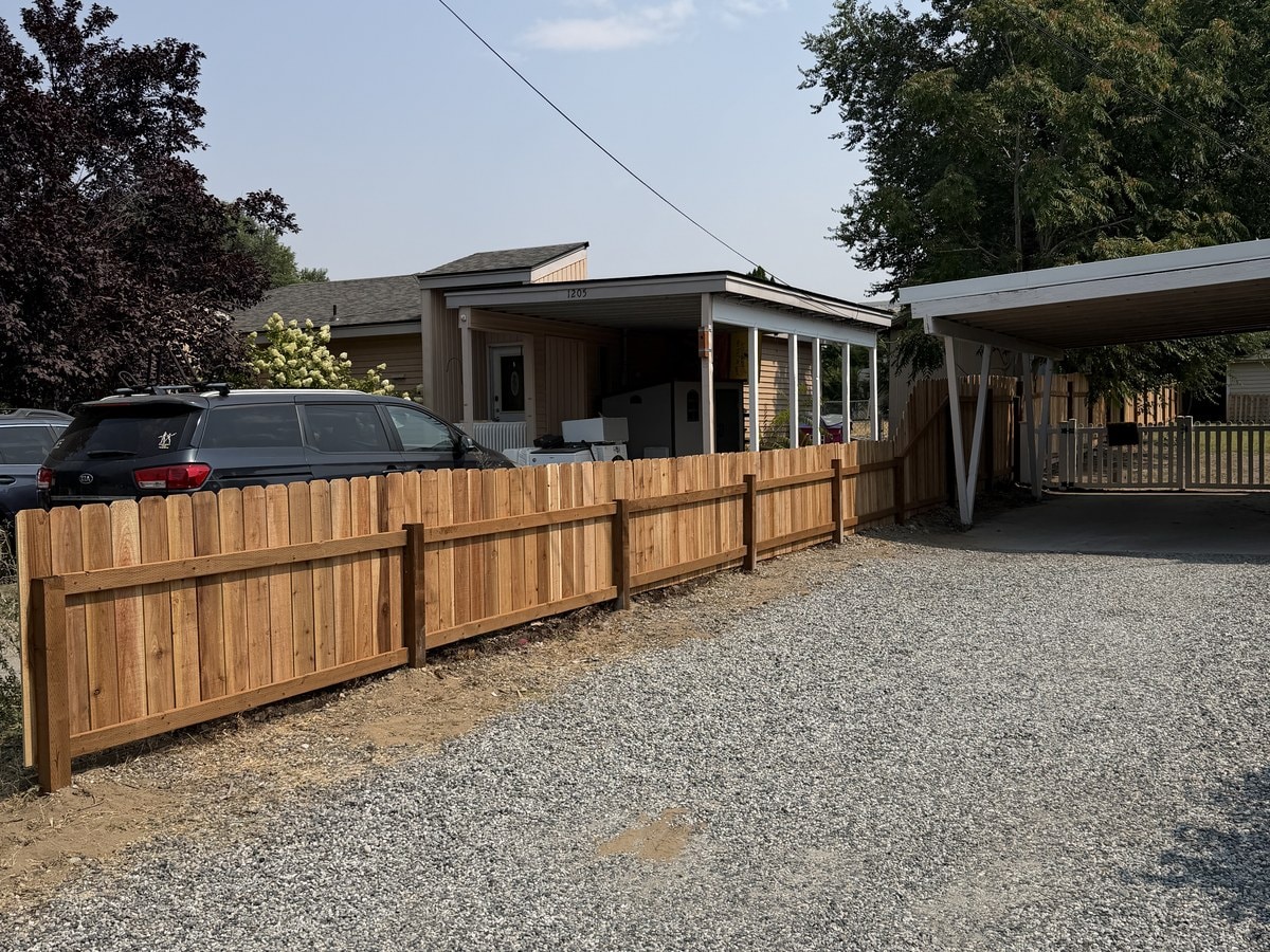The new cedar fence running the same length of gravel drive