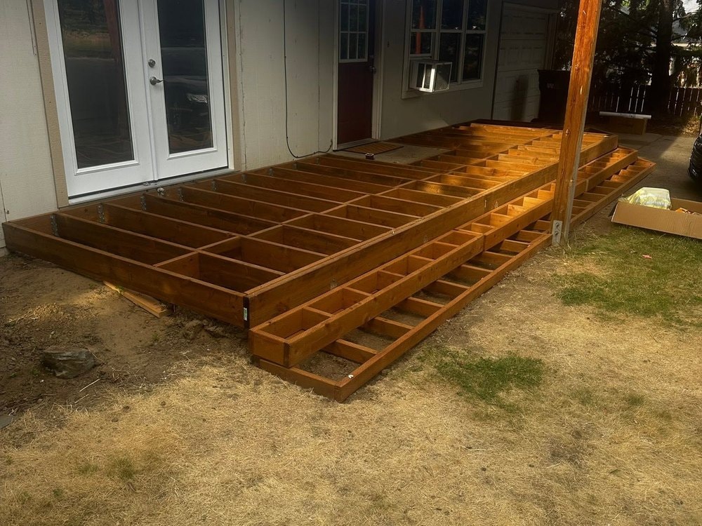 Framed joists spanning from the French doors out to the step tiers, seen from the yard