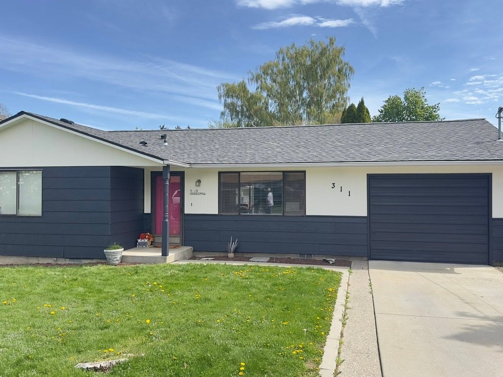 Front of the house in navy and cream with a pink door and navy garage door