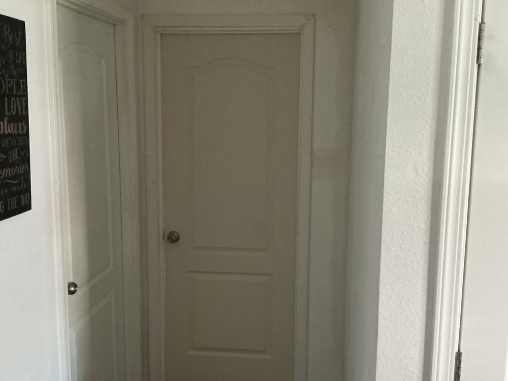 Closed white arch top panel door set in the hallway opening with casing installed around it