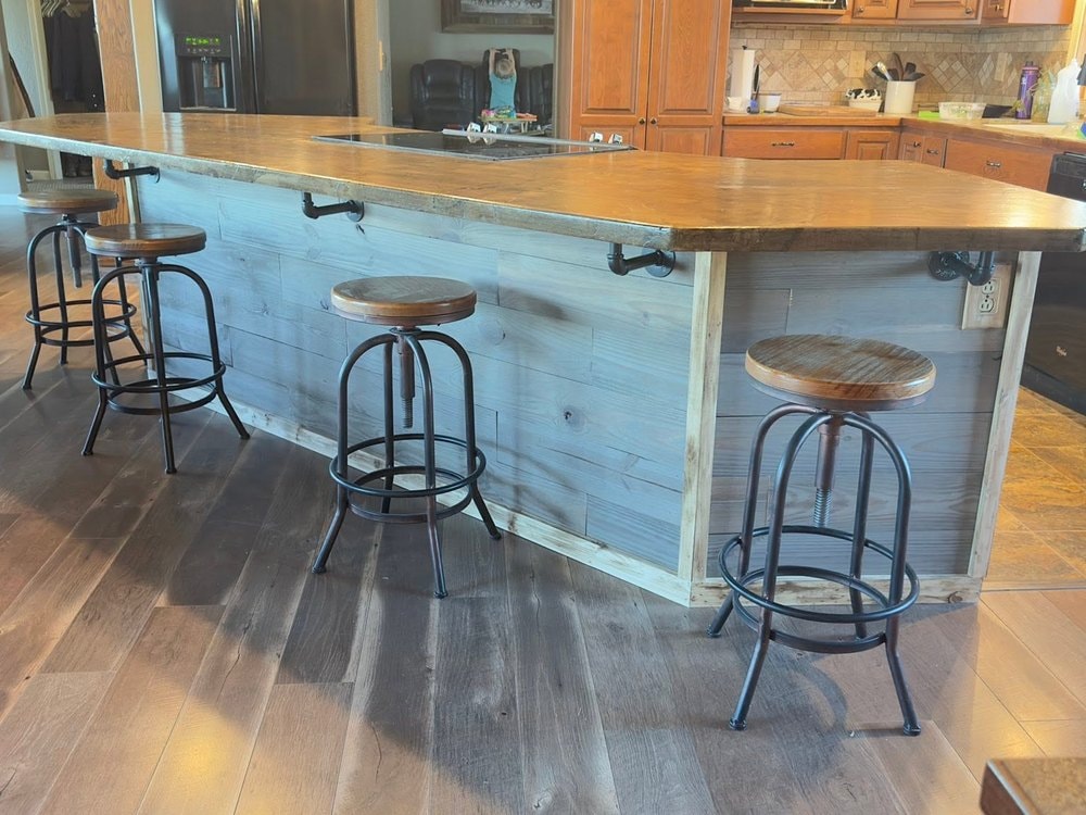 Blue grey plank island front with four metal stools along the single level counter