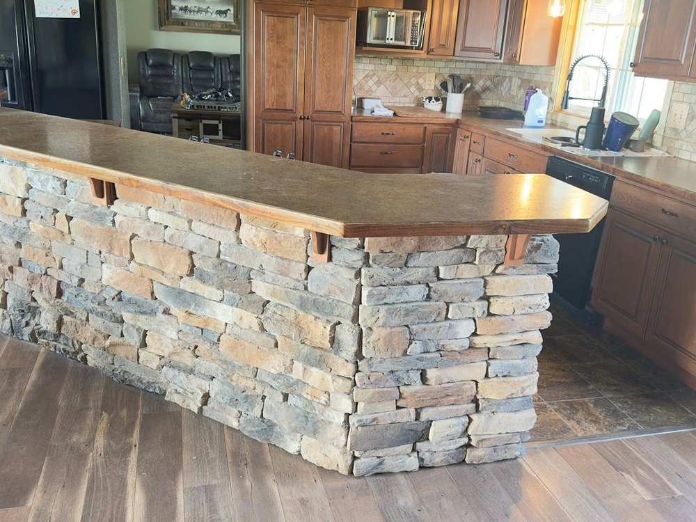 Stacked stone facing on the raised island bar with a wood edged counter above