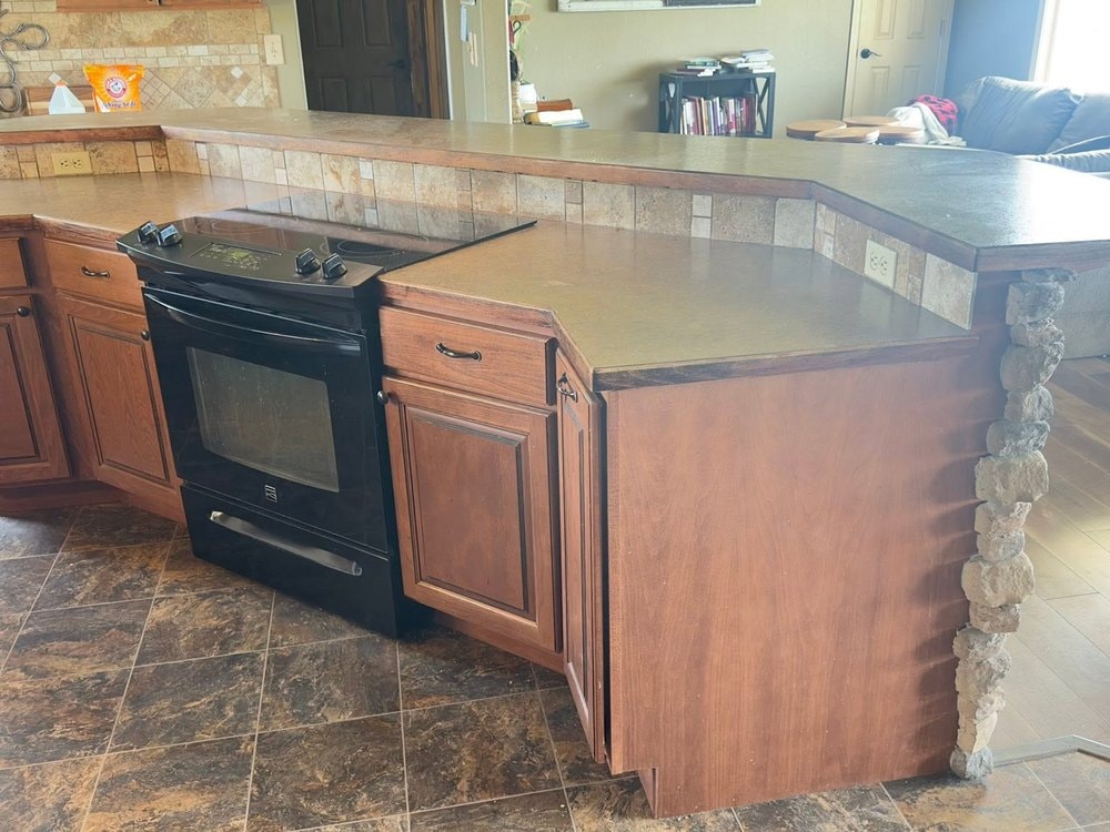 Black range set into the island with a tiled riser and raised counter behind it