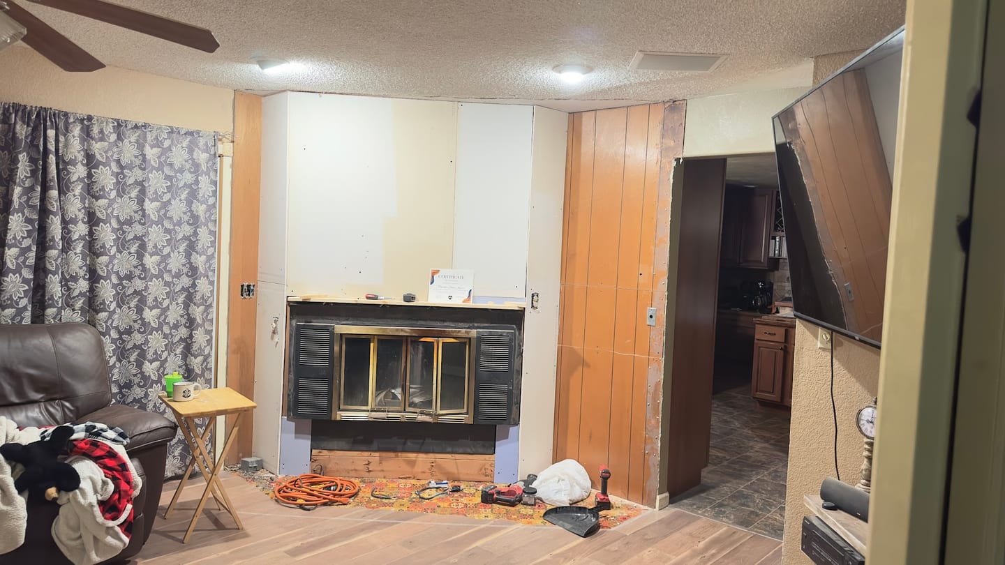 A wall-mounted television beside a fireplace during a living room rebuild